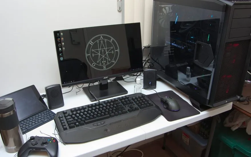A desktop gaming setup with an Acer monitor, keyboard, mouse, and gaming PC
